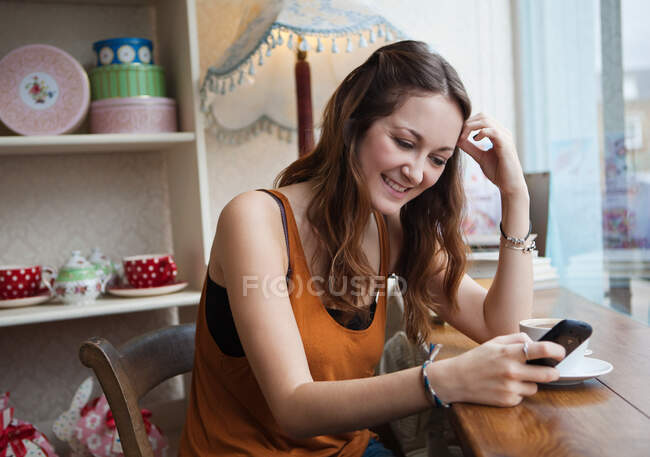 Молода жінка в кафе за допомогою мобільного телефону — стокове фото
