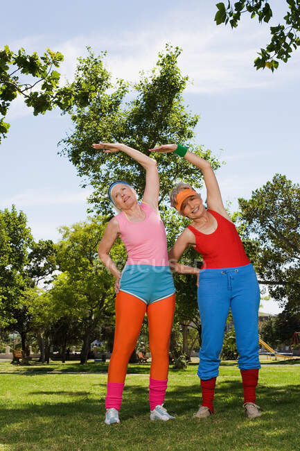 Two senior adult women stretching in park — Stock Photo