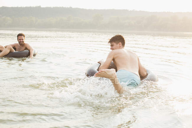 Amici che si divertono con anello gonfiabile nel fiume — Foto stock