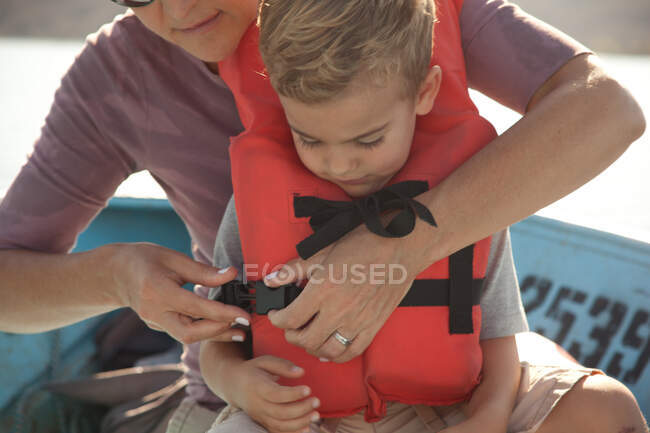 Mother fastening son's life jacket — Stock Photo