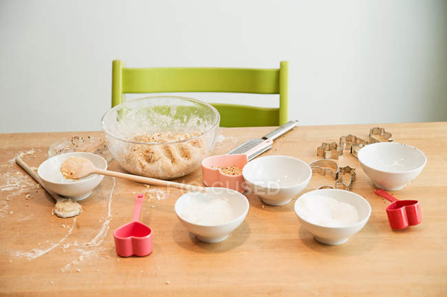 Batter in mixing bowl, ladle, baking molds on table — Stock Photo