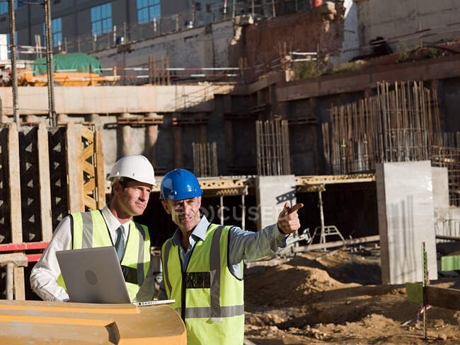 Mature men uusing laptop on construction site — Stock Photo
