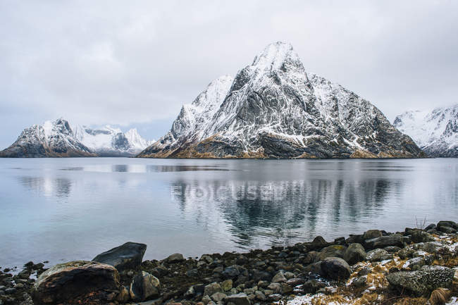 Coastline and snowcapped mountains reflecting in water — Stock Photo