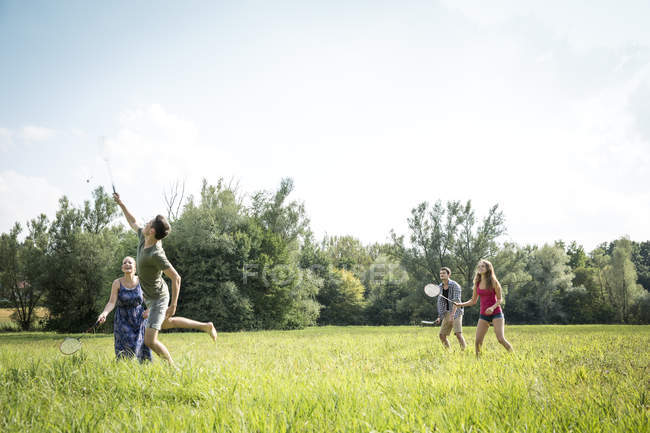 Group of young adults playing badminton in field — Stock Photo
