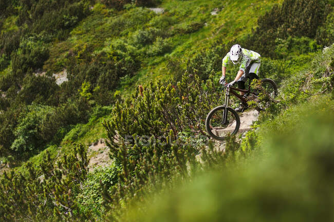 Montanha motociclista equitação para baixo íngreme colina caminho — Fotografia de Stock