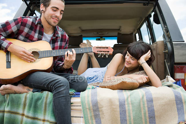 Joven tocando la guitarra con su novia - foto de stock