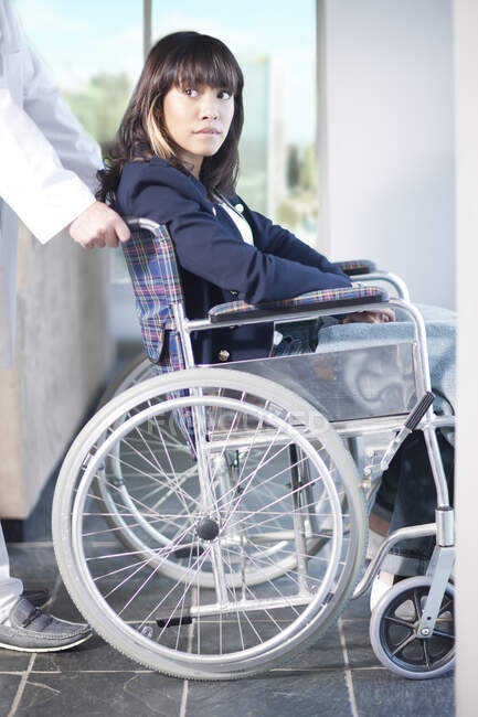 Mujer en silla de ruedas asistida por un enfermero - foto de stock