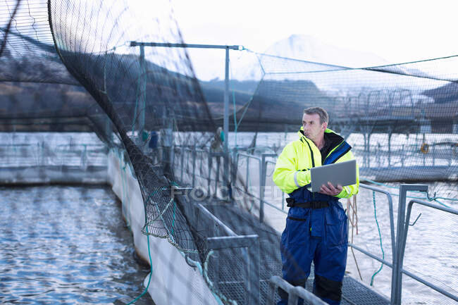 Travailleur utilisant un ordinateur portable à la salmoniculture — Photo de stock