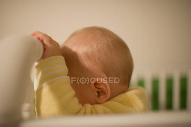 Toddler boy resting forehead on cot — Stock Photo