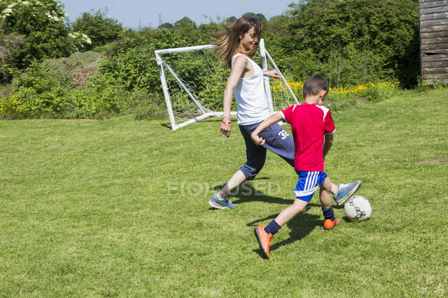 Мать и сын играют в футбол в саду — стоковое фото
