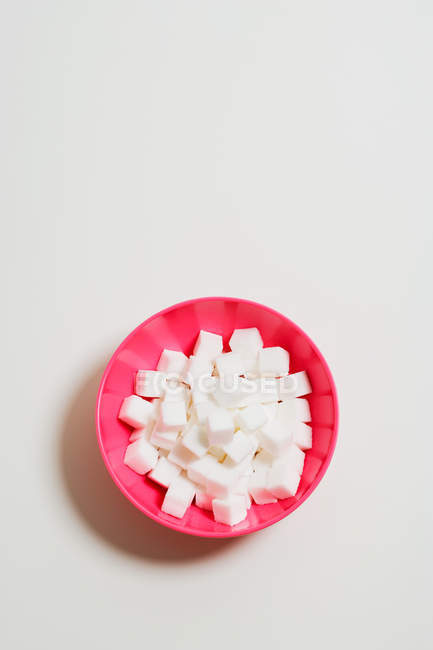 Pink bowl full of sugar cubes — Stock Photo