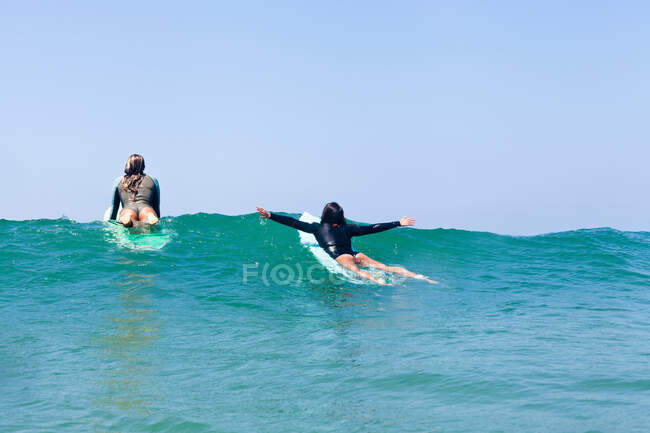 Amigas surfing, Hermosa Beach, California, EE.UU. - foto de stock