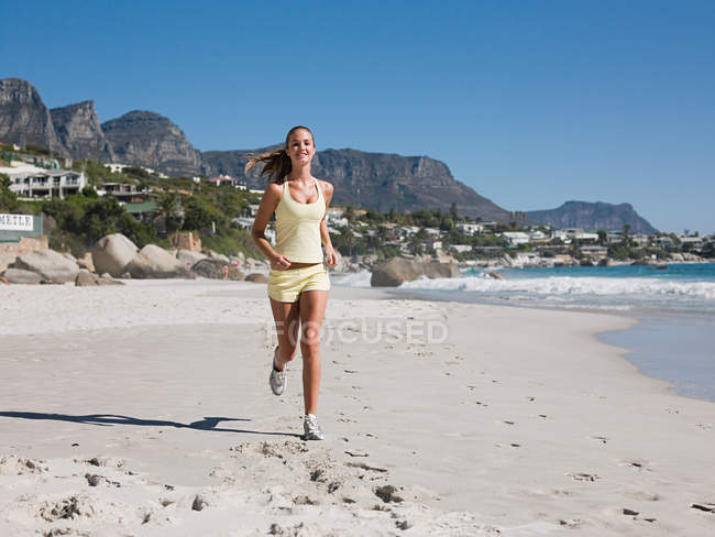 Jeune femme jogging sur la plage — Photo de stock