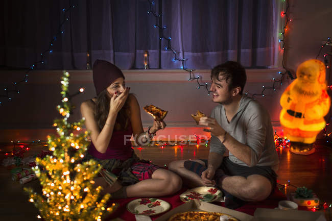 Young couple enjoying pizza at christmas — Stock Photo