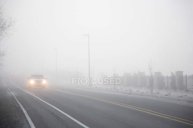 Туман на дороге с движущейся машиной — стоковое фото