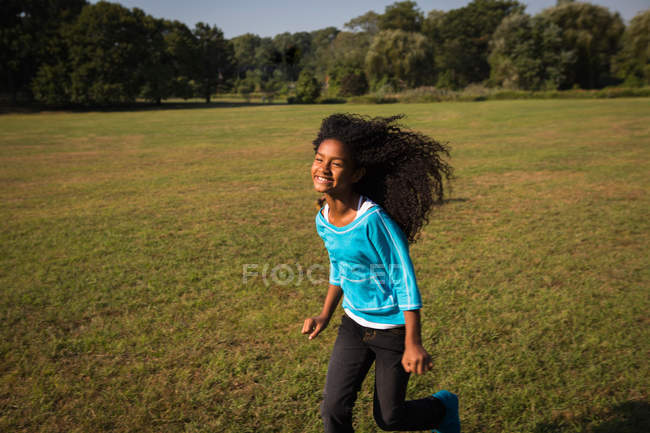 Усміхнена дівчина біжить у полі — стокове фото