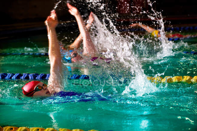 Female swimmers doing backstroke in swimming pool — Stock Photo
