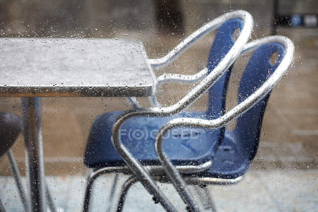 Журнальний столик і стільці через віконне скло в краплі дощу — стокове фото