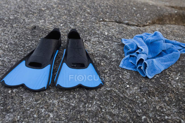 Blaue Schwimmflossen und Handtuch auf Steinoberfläche — Stockfoto