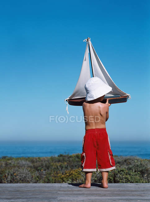 Хлопчик тримає іграшковий човен на відкритому повітрі — стокове фото