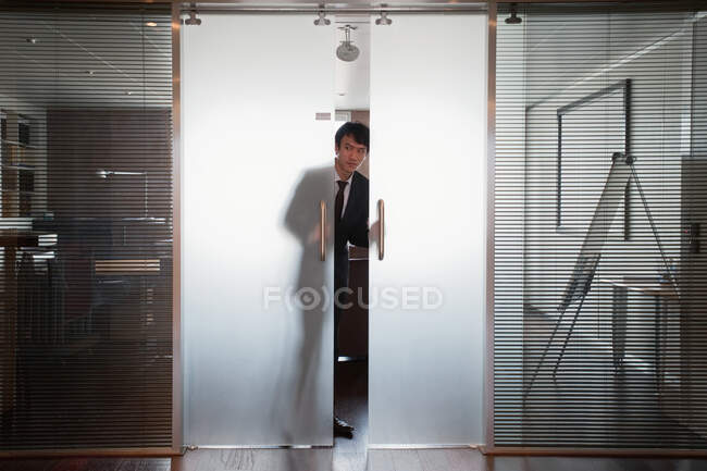 Geschäftsmann blickt aus doppelter Tür — Stockfoto