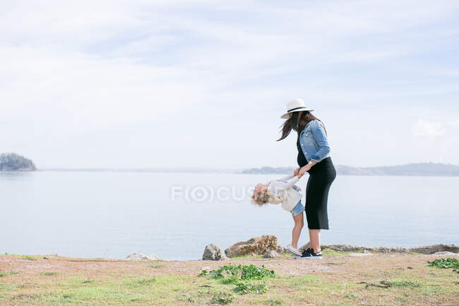 Pregnant mother playing with daughter at coast — Stock Photo