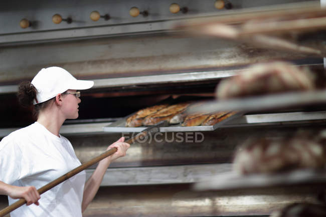 Baker putting bread on shelf — Stock Photo