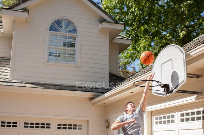 Зрелый мужчина играет в баскетбол возле гаража — стоковое фото