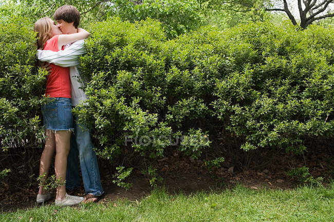 Teenager pärchen küssen sich im busch — Stockfoto