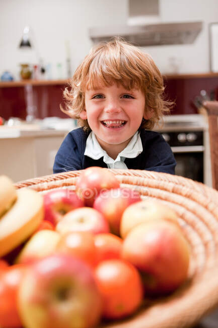 Мальчик сидит за обеденным столом с яблоками — стоковое фото