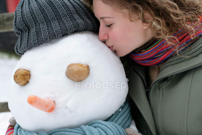 Femme embrassant un bonhomme de neige — Photo de stock