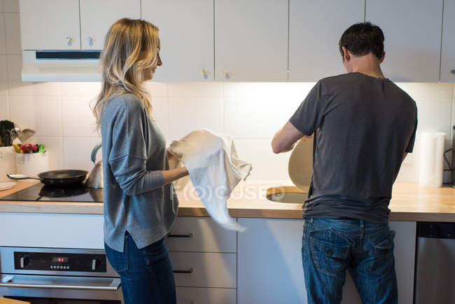 Mid adult couple washing plate at kitchen sink — Stock Photo