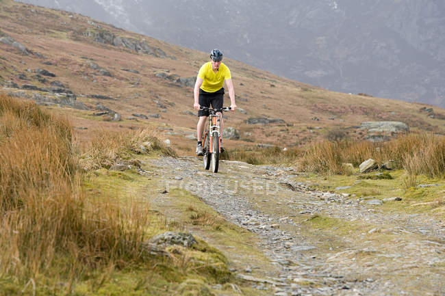 Un uomo in bicicletta sul sentiero — Foto stock