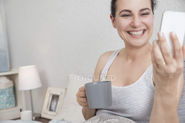 Femme prenant selfie avec smartphone au lit — Photo de stock
