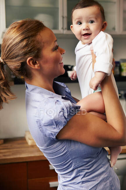 Madre sosteniendo a la niña, sonriendo - foto de stock