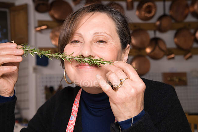 Woman smelling a sprig of rosemary — Stock Photo