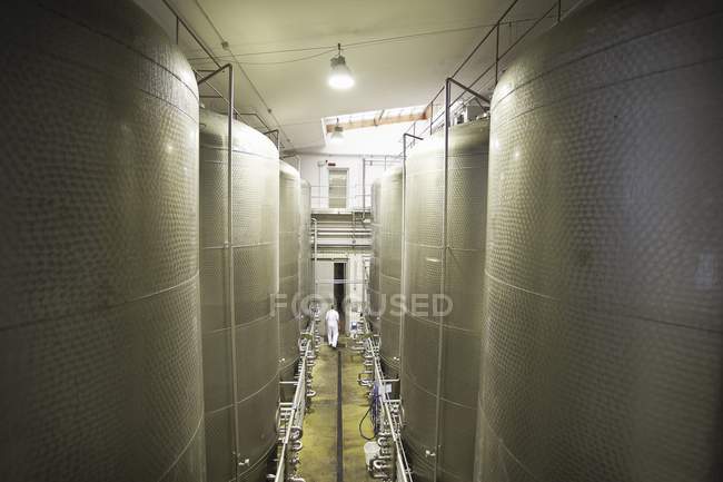 Large tanks in brewery with distant worker — Stock Photo