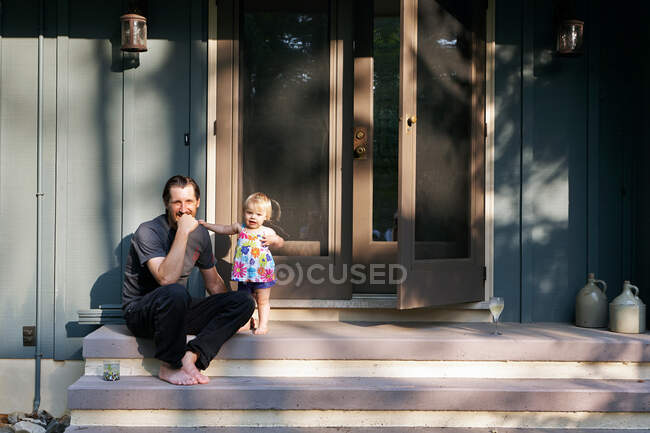 Mature man sitting on steps with young daughter, portrait — Stock Photo