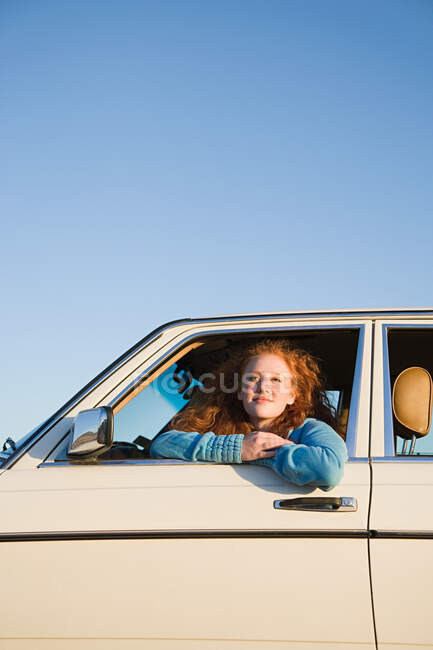 Une jeune femme penchée par la fenêtre d'une voiture — Photo de stock