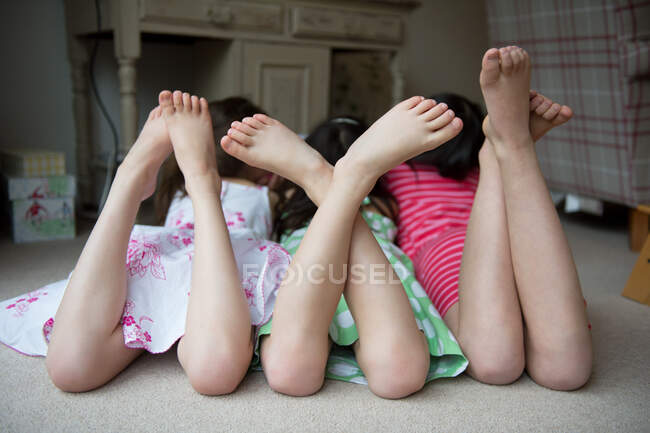 Chicas tumbadas en el suelo junto con los pies arriba - foto de stock