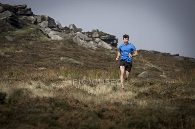 Male runner running down from Stanage Edge, Peak District, Derbyshire, UK — Stock Photo