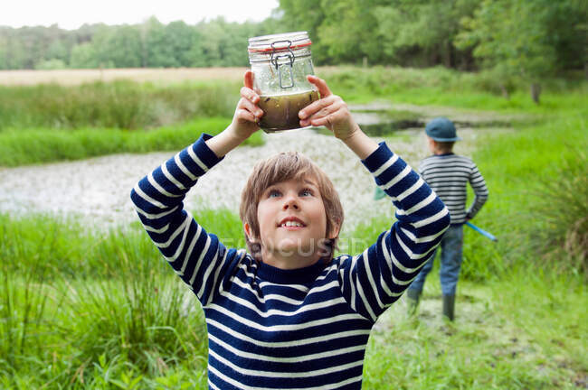 Boy looking at tadpoles in jar — Stock Photo