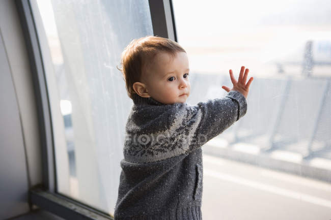 Menino tocando janela do aeroporto — Fotografia de Stock