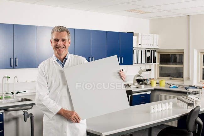 Cientista masculino com sinal em branco em laboratório — Fotografia de Stock