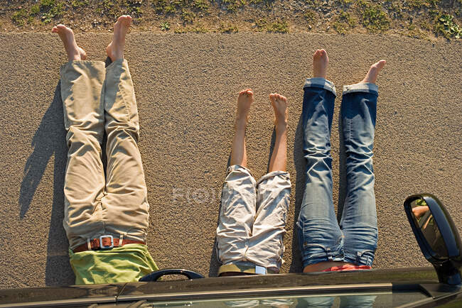 Família deitada debaixo de carro — Fotografia de Stock