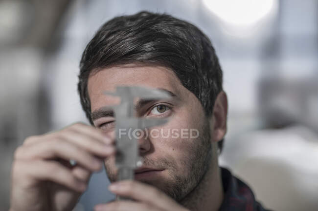 Cape Town, South Africa, close up of young man in workshop double checking measurments from his tool — Stock Photo