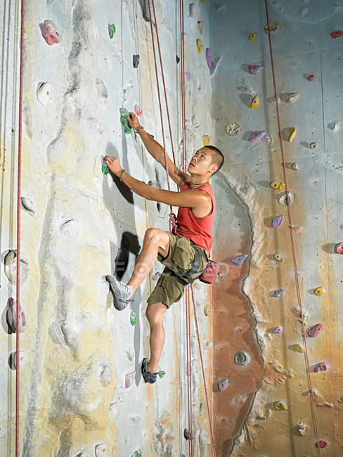 Asian Man on climbing wall — Stock Photo