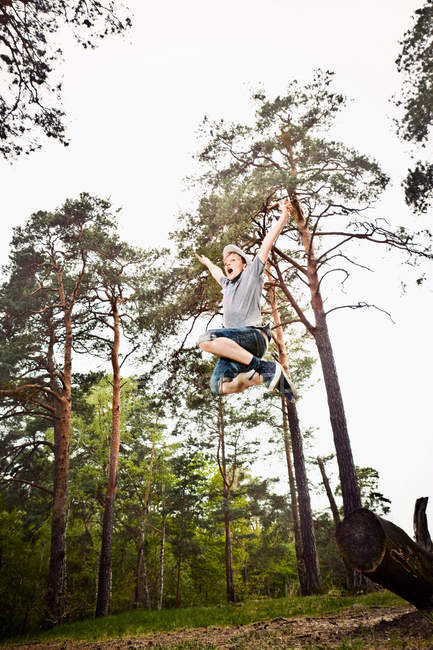 Rapaz saltando na floresta — Fotografia de Stock
