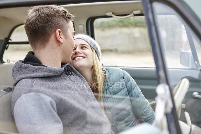 Romantic young couple in front seat of car at beach — Stock Photo