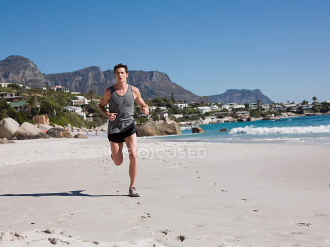 Молодой человек бегает по пляжу — стоковое фото